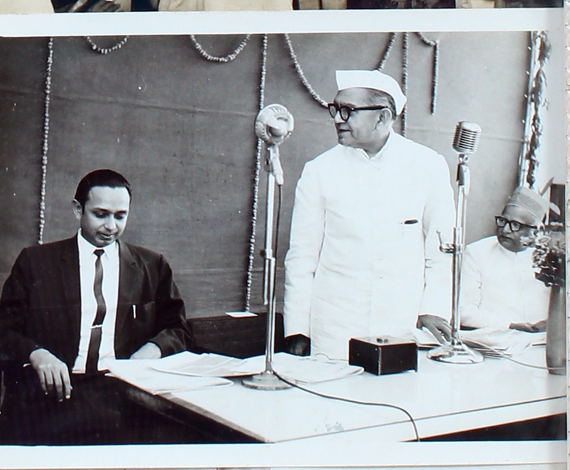 Three men at a head table with microphones during a meeting.